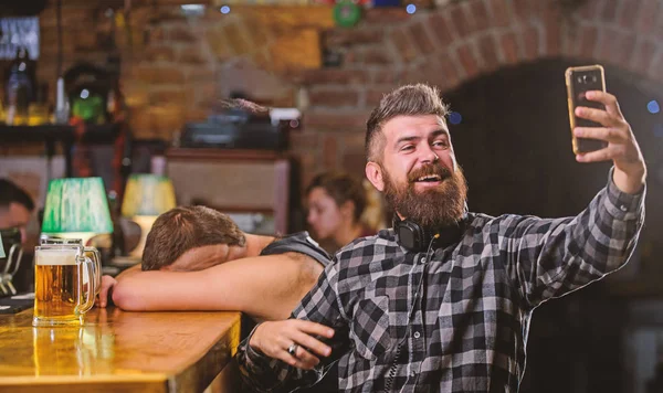 Man bebaarde hipster greep smartphone. Nemen selfie concept. Online communicatie. Selfie verzenden vrienden sociale netwerken. Man in bar bier drinken. Neem selfie foto om te onthouden van geweldige avond in de kroeg — Stockfoto