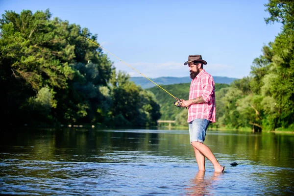 La pesca causa efectos fisiológicos negativos para las poblaciones de peces. El impacto medioambiental de la pesca incluye cuestiones como la disponibilidad de pescado. El hombre a orillas del río disfrutar de un paisaje idílico mientras pesca —  Fotos de Stock