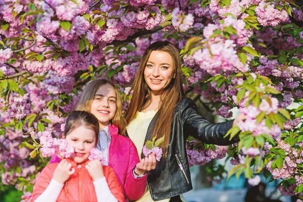 small children and mother in spring flower. happy sisters in cherry flower. Sakura bloom. family summer. Natural beauty. Mothers day. blossom smell, allergy. Sisterhood. New green life