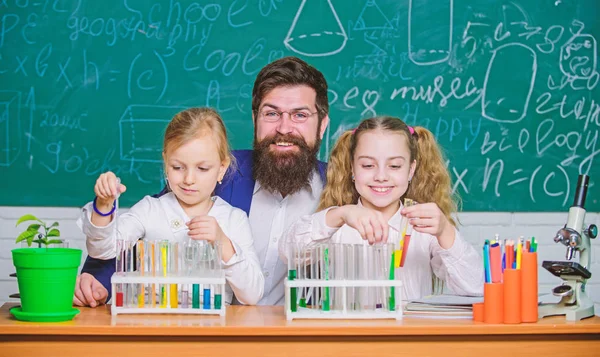 Research studies. Science teacher and pupils doing research work. Teacher and primary school children holding test tubes in research laboratory. Experimental research is conducting a laboratory test