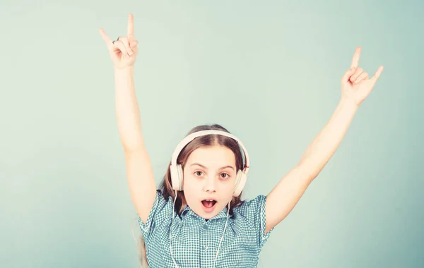 Shes a rock star. Little kid showing horn hand gesture like a hard rock or heavy metal fan. Cute small child listening to rock music playing in headphones. Adorable girl enjoying punk rock music