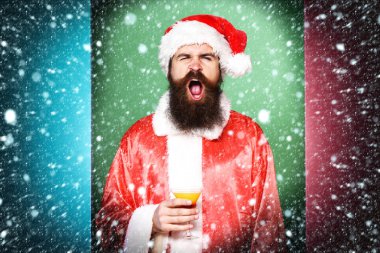 renkli stüdyo backgroun üzerinde noel veya xmas kazak ve yeni yıl şapka alkollü içecek cam tutan komik yüzünde uzun sakallı yakışıklı sakallı noel baba adam
