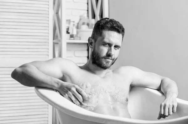 Laver soigneusement la mousse avec de l'eau. Concept de sexe et relaxation. Macho nue dans la baignoire. homme laver le corps musculaire avec mousse éponge. Macho appréciant le bain. Homme sexy dans la salle de bain. Tu as bonne mine — Photo