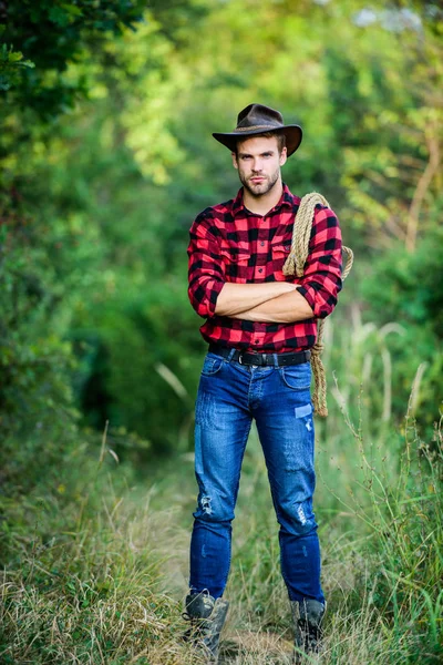 El hombre con sombrero sostiene la cuerda. Propietario del rancho. concepto de cría attle. Vaquero en el campo. Ocupaciones de rancho. Herramienta Lasso. Vaquero americano. Lasso atado envuelto. La vida occidental. Hombre vaquero naturaleza backgroun —  Fotos de Stock