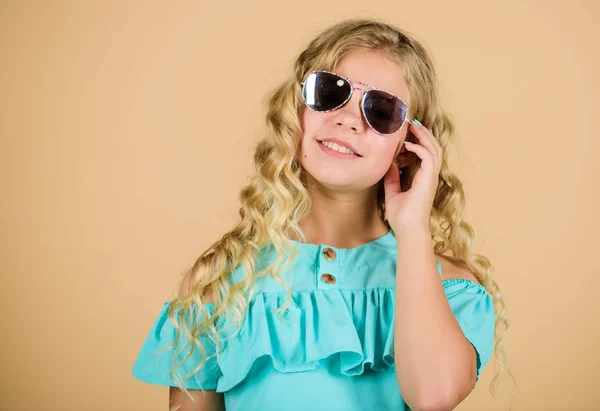 Following her personal style. happy little girl with long healthy hair. kid summer fashion. beauty and fashion. long blond curly hair. beautiful little girl in sunglasses. trendy fashion model