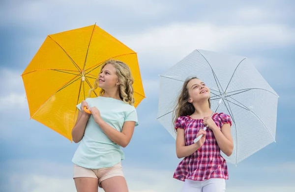 Bambini spensierati all'aperto. Ragazze amiche con ombrelli cielo nuvoloso sfondo. Libertà e freschezza. Previsioni meteo. Pronti per qualsiasi tempo. Vento o piovoso siamo preparati. Cambiamenti climatici — Foto Stock