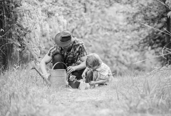 Azienda agricola ecologica. annaffiatoio, pentola e zappa. Attrezzature da giardino. bambino piccolo aiutare il padre in agricoltura. padre e figlio col cappello da cowboy al ranch. Buon Giorno della Terra. Allevamento alberi genealogici. Aiuto e supporto — Foto Stock