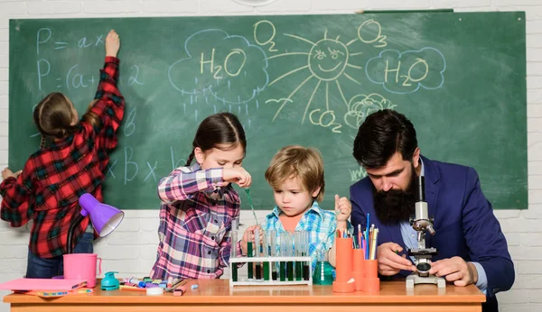 Explicando química a los niños. Fascinante lección de química. Profesor barbudo y alumnos con tubos de ensayo en clase. Observa la reacción. La ciencia es siempre la solución. Experimento de química escolar — Foto de Stock