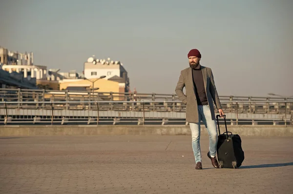 Business trip. Man bearded hipster travel with big luggage bag on wheels. Let travel begin. Traveler with suitcase arrive to airport railway station. Hipster ready enjoy travel. Carry travel bag