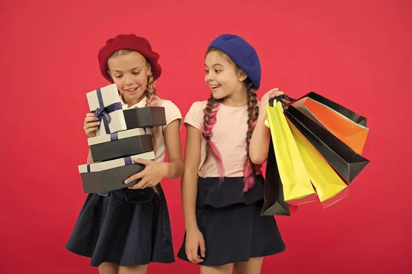 Концепция шопоголика. Шоппинг становится весело с лучшими друзьями. Дети милые школьницы держат кучу сумок для покупок. Дети довольны покупками на красном фоне. Одержимый магазинами и магазинами одежды — стоковое фото