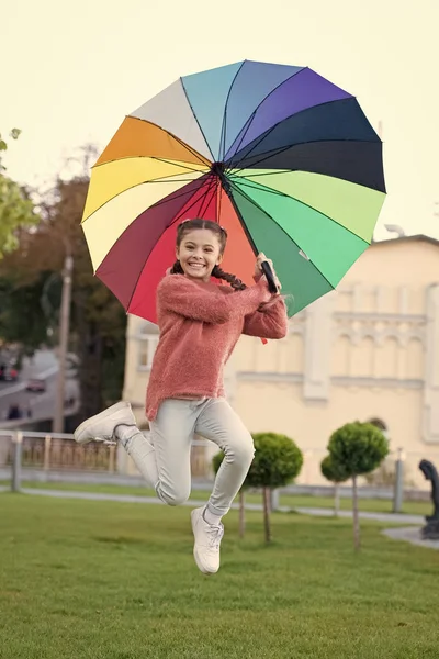 Feliz y libre. niño alegre. Estilo primavera. Arco iris después de la lluvia. Niña bajo paraguas colorido. El estado de ánimo positivo en el clima de otoño. Paraguas multicolor para niña feliz. Sentirse feliz — Foto de Stock