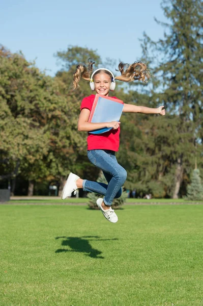 Šťastné učení. Dívka poslouchající hudbu moderní gadget. Kid happy wireless headset running with school books. Stereo sluchátka. Kluk používající moderní technologii. Moderní školačka. Radost z učení. Bav se — Stock fotografie