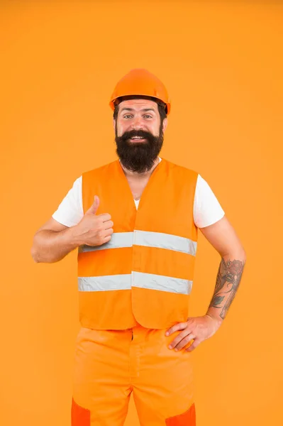 Der Meister, mit dem man bauen kann. Bauingenieur oder Architekt zeigt Daumen hoch für ein neues Bauprojekt. Glückliche Bauarbeiter oder Bauarbeiter lächeln auf orangefarbenem Hintergrund. Konstruktion und Bau — Stockfoto