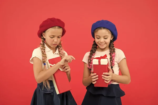 Kinderen van kleine meisjes in schooluniform en baretten houd geschenken vakken. Kinderen enthousiast over het uitpakken van de cadeaus. Kleine schattige meisjes ontvangen giften van de vakantie. Het brengen van geluk aan kinderen. Beste giften voor jonge geitjes — Stockfoto