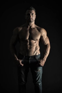 O doğuştan bir atlet. Siyah arka planda seksi atlet. Yakışıklı adam kas altı paketi abs gösteren. Atlet veya uygun güçlü gövde li atletik adam kot giyiyor