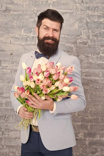 Guide for modern man. Romantic man with flowers. Romantic gift. Macho getting ready romantic date. Tulips for sweetheart. Man well groomed tuxedo bow tie hold flowers bouquet. How to be gentleman
