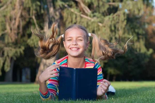 Bedårande Bookworm. Skol läsning berättelser avkopplande grön gräsmatta. Söt elev tycker om att läsa. Skoltid. Utveckla omtänksamma elever som aktivt växer och uppnår. Lilla barn läsebok — Stockfoto