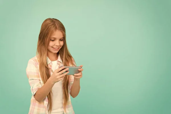 Pretty blogger. Small girl child with smartphone. Small girl using mobile phone. Adorable child learning new technology. Cute mobile phone technology user. Watching video on mobile device, copy space