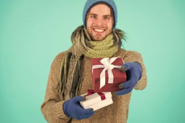 Senin için bir şeyim var. Hipster, Noel hediyesini yaylı tut. Tatil hediyesi konsepti. Kış tatili Hediye vermek mutluluğu yayar. Sakallı yakışıklı, kışlık şapka takıyor. Eldivenlerde hediye kutusu var.