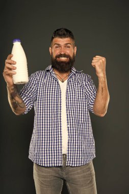 Süt ürünleri iyi protein ve kalsiyum kaynaklarıdır. Sakallı adam gri arka planda bir şişe süt içeceği tutuyor. Süt diyetinin tadını çıkaran mutlu hipster. Süt menüsü