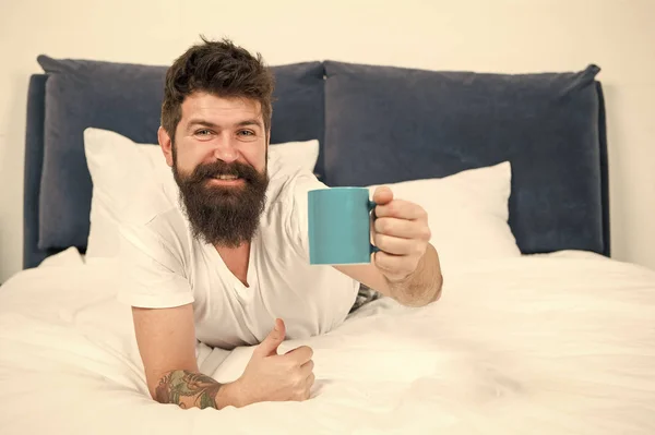 Voici votre café du matin. homme endormi brutal dans la chambre. mâle mature avec barbe en pyjama sur le lit. endormi et réveillé. énergie et fatigue. heureux homme barbu boire le café du matin. Tôt le matin — Photo