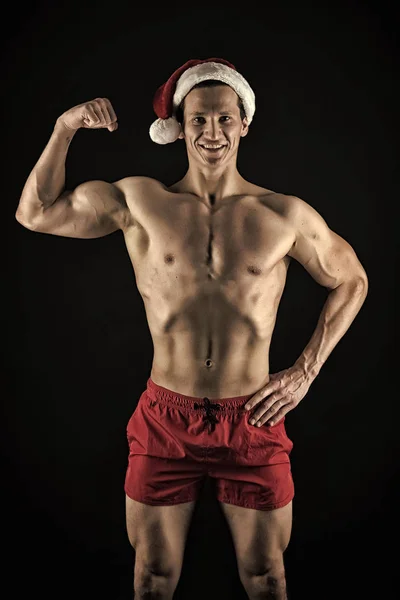 New year party. Santa claus man. Present for Xmas. Happy winter holidays. Red. Christmas shopping. Sexy muscular man in santa hat. Sport. Merry Christmas and Happy Holidays