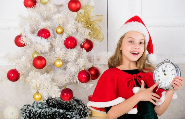 메리 크리스마스 개념입니다. 새해 카운트 다운. 여자 아이 산타 모자 의상 홀드 시계 흥분 행복 한 얼굴 표정 새해에 시간을 계산. 자정까지 마지막 순간. 마지막 순간 새해 전야 계획 — 스톡 사진
