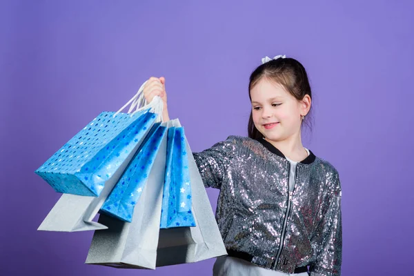 Černý pátek. Prodejní sleva. V den nakupování. Dítě drží balík. Dětský móda. Oslavenkyně. Překvapivý dárek. Dívka s nákupními taškami fialovou pozadí. Nakupování a nákup. Lépe se dívat — Stock fotografie