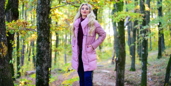 Jackets everyone should have. Best puffer coats to buy. How to rock puffer jacket like a star. Puffer fashion concept. Girl fashionable blonde walk in autumn forest. Woman wear warm pink jacket