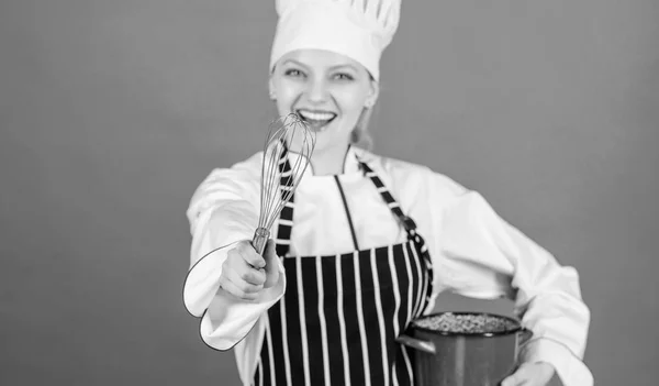 Azotando como profesional. Chica en delantal batiendo huevos o crema. Empieza a batir lentamente batiendo o batiendo crema. Usa un batidor de manos. Azotar consejos de crema y trucos. Mujer profesional chef hold batidor y olla — Foto de Stock