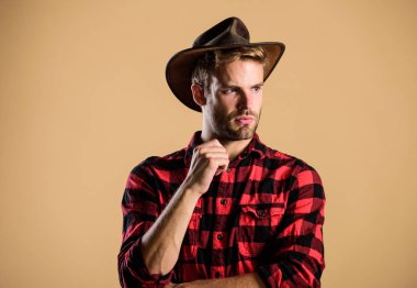 Yakışıklı sakallı maço. Amerikan kovboyu. Güzellik standardı. Gerçek erkeklik örneği. Şapka takan kovboy. Batı hayatı. Adam traşsız kovboy bej arka plan. Kovboy şapkalı traşsız adam