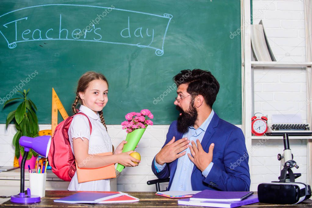 Greetings for school pedagogue. School holiday. Thankful schoolgirl. Back to school. Best wishes. Girl adorable pupil with backpack giving bouquet flowers teacher. Knowledge day congratulations