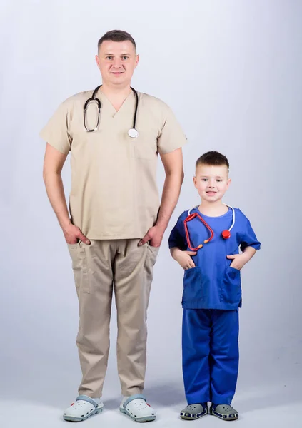 Husläkare. Barnläkare koncept. Fader läkare med stetoskop och Lille son läkare uniform. Medicin och hälsovård. Framtida yrke. Vill vara doktor som pappa. Söt unge spela läkare spel — Stockfoto
