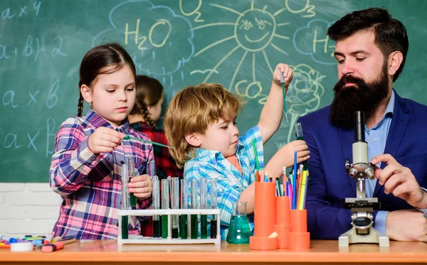 Schulclubausbildung. Lehrer und Schüler testen Röhren im Klassenzimmer. Chemie-Themenclub. Eigenschaften von Substanzen gemeinsam entdecken und erforschen. Interessen und Themenclub. Ältere Kinder helfen Jüngeren — Stockfoto