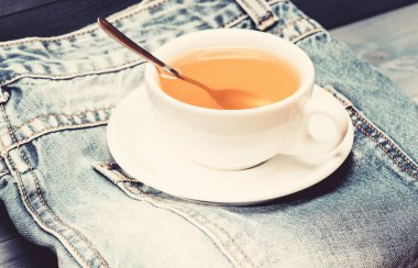 Sağlıklı alışkanlıklar. Çay saati konsepti. Fincan bardağı sıcak su ve çay torbası. İşlem çay seramik kupa demleme. Bitkisel yeşil veya siyah bütün yaprak. Kupa dolu kaynar su ve çay poşeti mavi kot arka plan üzerinde