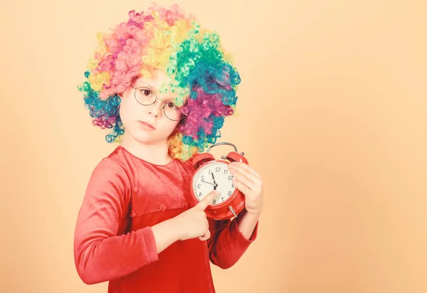 Happy little girl. International childrens day. Child care. Happy moments. Kid hold alarm clock. Stop being so serious. Girl cute playful kid wear curly rainbow wig. Life is fun. Happy childhood — Stock Photo, Image