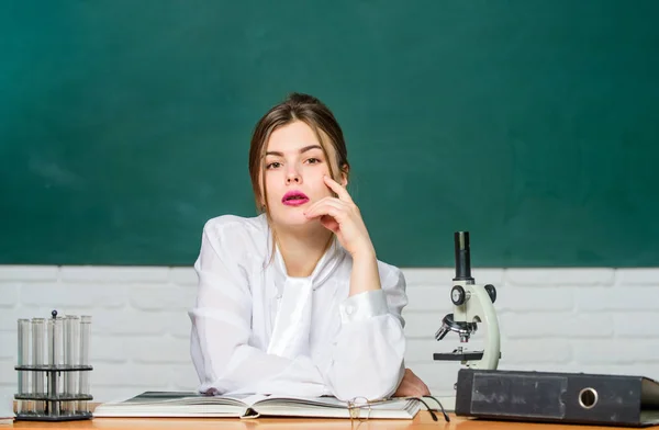 Vetenskaplig forskning. Utbildningskoncept. Kvinna ganska bedårande lärare eller student. Kemist biolog med Mikroskop. Biologi student sitta klassrummet svarta tavlan bakgrund. Smart student. Studera hårt — Stockfoto