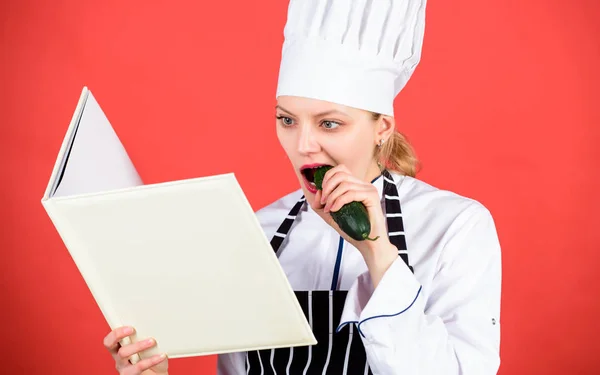 Mitt jobb. kvinna i hatt och förkläde. Hemmafru med kokbok. restaurangmeny. Kulinariska bantning. professionell i köket äta gurka. Rätter. lycklig kvinna matlagning hälsosam mat med recept — Stockfoto