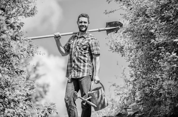 Elija pisos plantas favoritas. Consejos profesionales de jardinería. Jardinería de primavera. Hombre barbudo hipster mantenga pala y regadera. Lista de verificación de jardinería de primavera. Es hora de plantar preparar camas y cuidar el césped —  Fotos de Stock