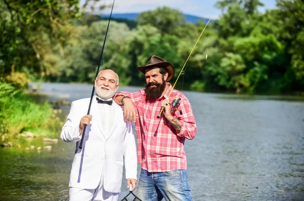 Aprender del profesional. hobby del hombre de negocios. pesca de jubilación. amigos hombres con caña de pescar. Vuela aventuras de pesca. pescadores felices en el agua. padre jubilado e hijo maduro con barba —  Fotos de Stock