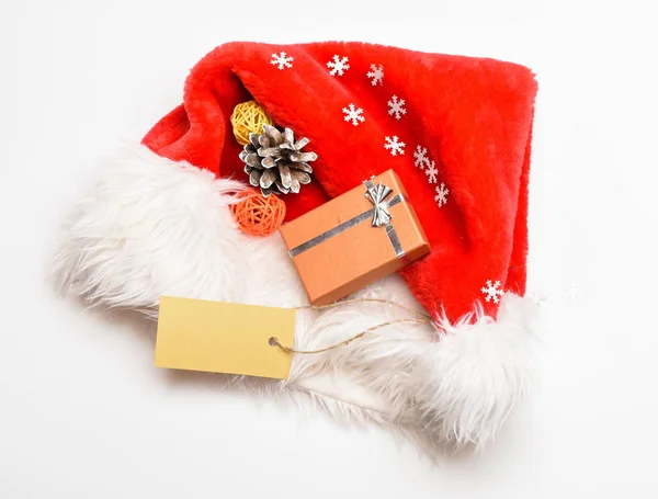 寒假的属性。新年和圣诞节庆祝。圣诞老人红帽子白色背景顶视图。带有圣诞礼盒的圣诞老人帽子。保持家庭传统。圣诞老人的圣诞礼物 — 图库照片