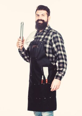 Açık havada et kavurma araçları. Piknik ve barbekü. Parkta et pişirmek. Barbekü ustası. Sakallı hipster barbekü için önlük giyer. Kavurma ve ızgara yemeği. Adam pişirme gereçleri barbekü tutun
