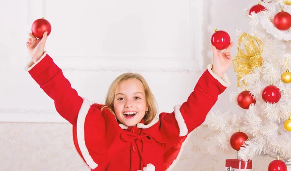 Menina sorridente rosto segurar bolas ornamentos fundo interior branco. Deixe a criança decorar a árvore de Natal. Parte favorita de decoração. Envolver a criança na decoração. Como decorar a árvore de Natal com a criança — Fotografia de Stock