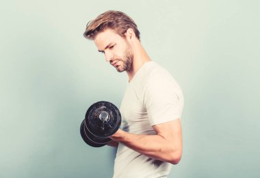 Yakışıklı adam egzersiz. Spor salonunda egzersiz yapmak. Dambılla egzersiz icra eden kaslı bir adam. Sporcu güçlü kasları antrenman. Spor ekipmanları. Fitness ve vücut geliştirme sporu. Spor yaşam tarzı. Spor motivasyonu