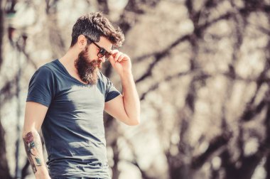 UV filtresi. Sakallı hippi vahşi adam koruyucu güneş gözlüğü takıyor. Güneş gözlüklü, sakallı, doğa geçmişi olan bir adam. Hippi koyu güneş gözlüklerine güveniyor. Sakallı adam modern güneş gözlüğü takıyor.