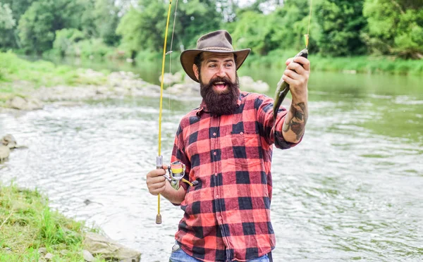 La pesca requiere ser consciente y estar plenamente presente en el momento. Equipo de pesca Fisher. Descanso y recreación. Pescado en gancho. Hombre brutal parado en el agua del río. Hombre barbudo pescador. Fisher pasatiempo masculino —  Fotos de Stock