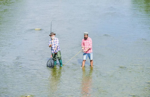 Männerfreundschaft. Vater und Sohn angeln. Gemeinsam angeln. Lehre den Menschen fischen, und du fütterst ihn ein Leben lang. Sommerwochenende. Glücklicher Fischer mit Angel und Netz. Hobby und sportliche Aktivität — Stockfoto