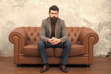 Şık ama sıradan. Sakallı adam kanepede dinleniyor. Gayri resmi takım giyen adam ya da iş adamı. Uzun sakallı ve modaya uygun saç stili olan moda adamı. Hipster yaşam tarzını takip eden zalim bir adam.