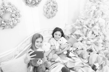 Ateş, upload ve paylaşın. Mutlu Noeller ve mutlu yeni yıl anılar. Cep telefonu ile mutlu küçük çocuklar. Küçük kız yatakta telefon kullanın. Noel ve yeni yıl selfie smartphone ile alarak