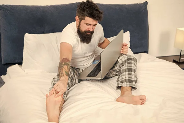 İletileri kontrol ediyorum. yatakta pijama sakallı olgun erkek. uykuda ve uyanık. enerji ve yorgunluk. bilgisayarlı işadamı. sakallı adam hipster dizüstü bilgisayarda çalışır. yatak odasında acımasız uykulu adam — Stok fotoğraf